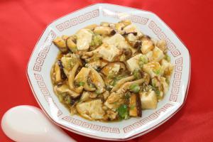 赤いテーブルクロスの上に置かれた中華皿に盛られている麻婆豆腐の写真
