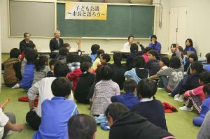 平成18年の子ども会議にて、塩嶺野外活動センターで床に座った中学生らと市長、教育長と意見交換を行っている写真