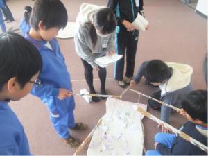 生徒たちが床に置かれた手作りの看板を作成している写真