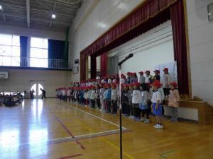 体育館で子供たちが舞台側に集まり並んでいる写真