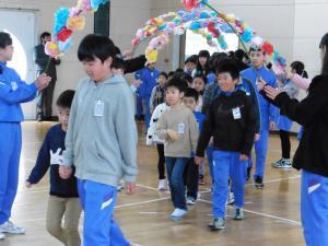 手をつないで花のアーチをくぐる子どもたちの写真