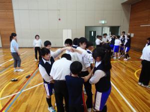 体育館に2名の生徒が手をつないで作った輪をくぐっている写真