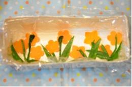 底に人参・絹さやで作られた花が配置された押し寿司の型の写真