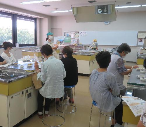 栄養講座の調理デモンストレーションで料理の説明を栄養士がしているところ