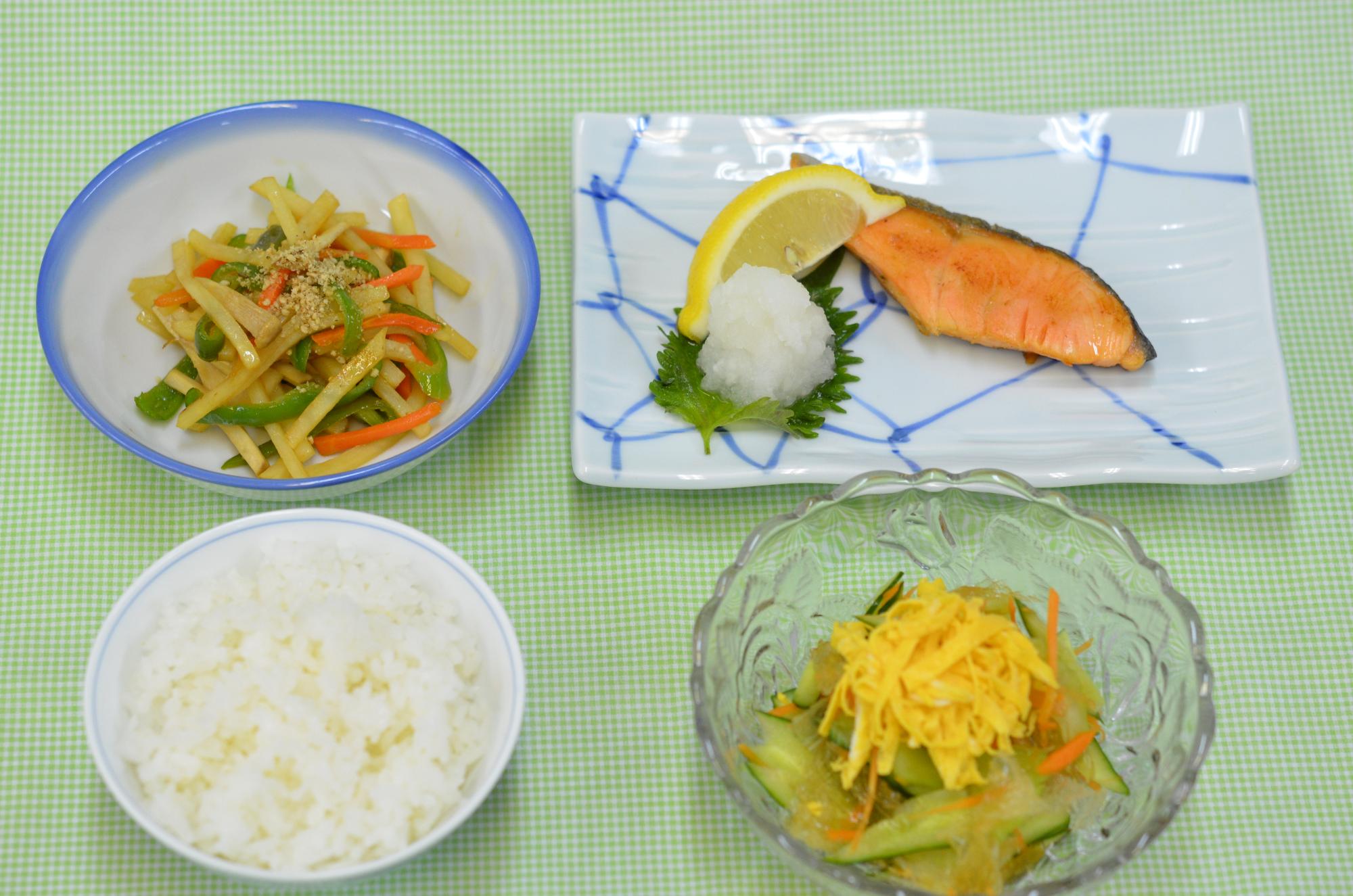 ごはんや焼き魚、炒め物、サラダの写真