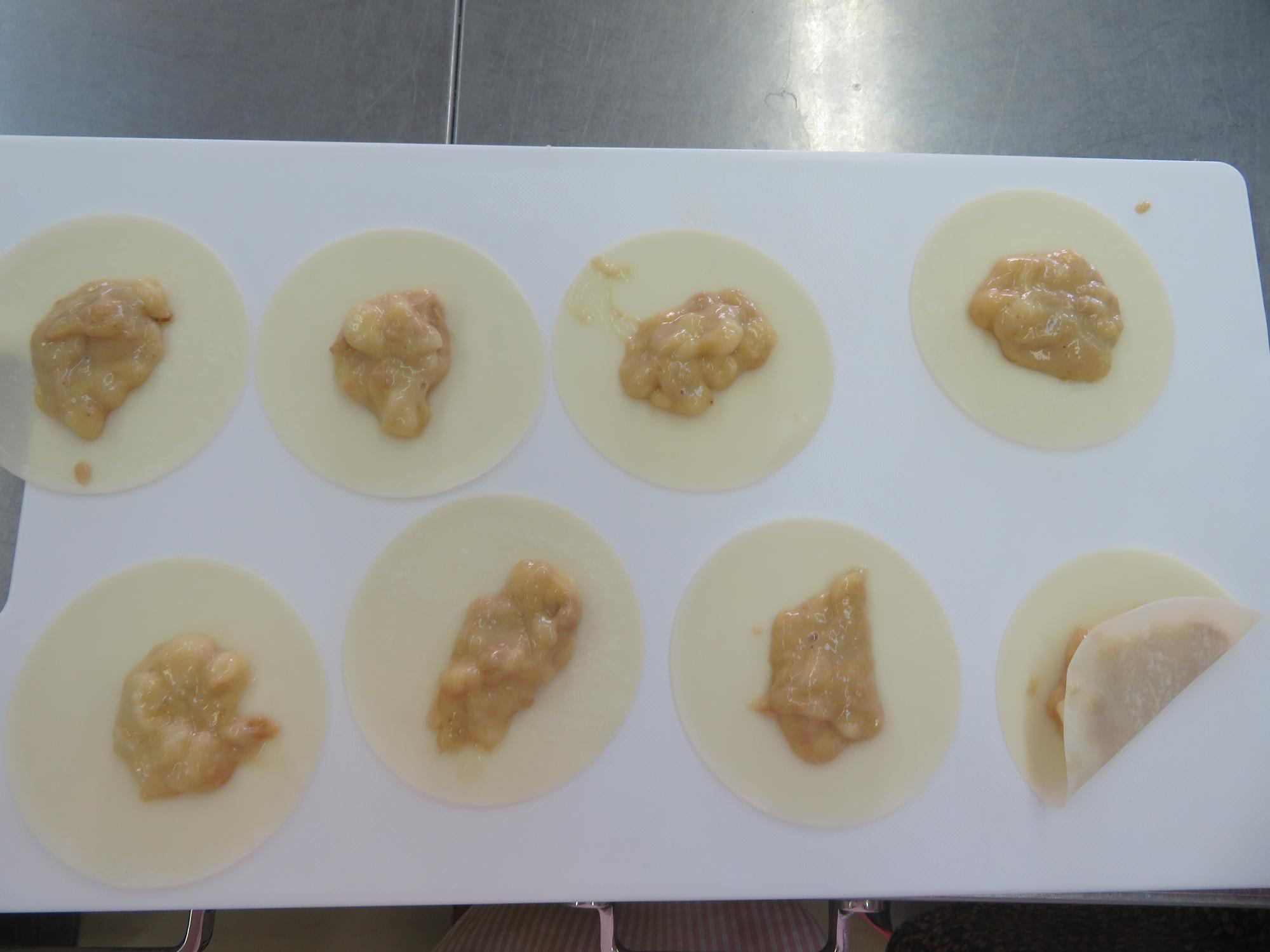生地を餃子の皮にのせて包む写真
