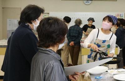 料理のデモンストレーションを参加者が見ている様子