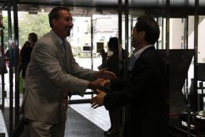 歓迎セレモニーにて笑顔で握手を交わす訪問団の外国人男性と日本人男性の写真