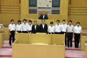 岡谷市役所議場にて、スーツを着た男性3人とその両脇に並ぶ9人の中学生の集合写真