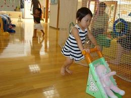 小さな女の子がベビーカーにぬいぐるみを乗せてお買い物ごっこ遊びをしている写真