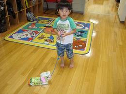 男の子が紙で作ったわんちゃんを引っ張って散歩ごっご遊びをしている写真