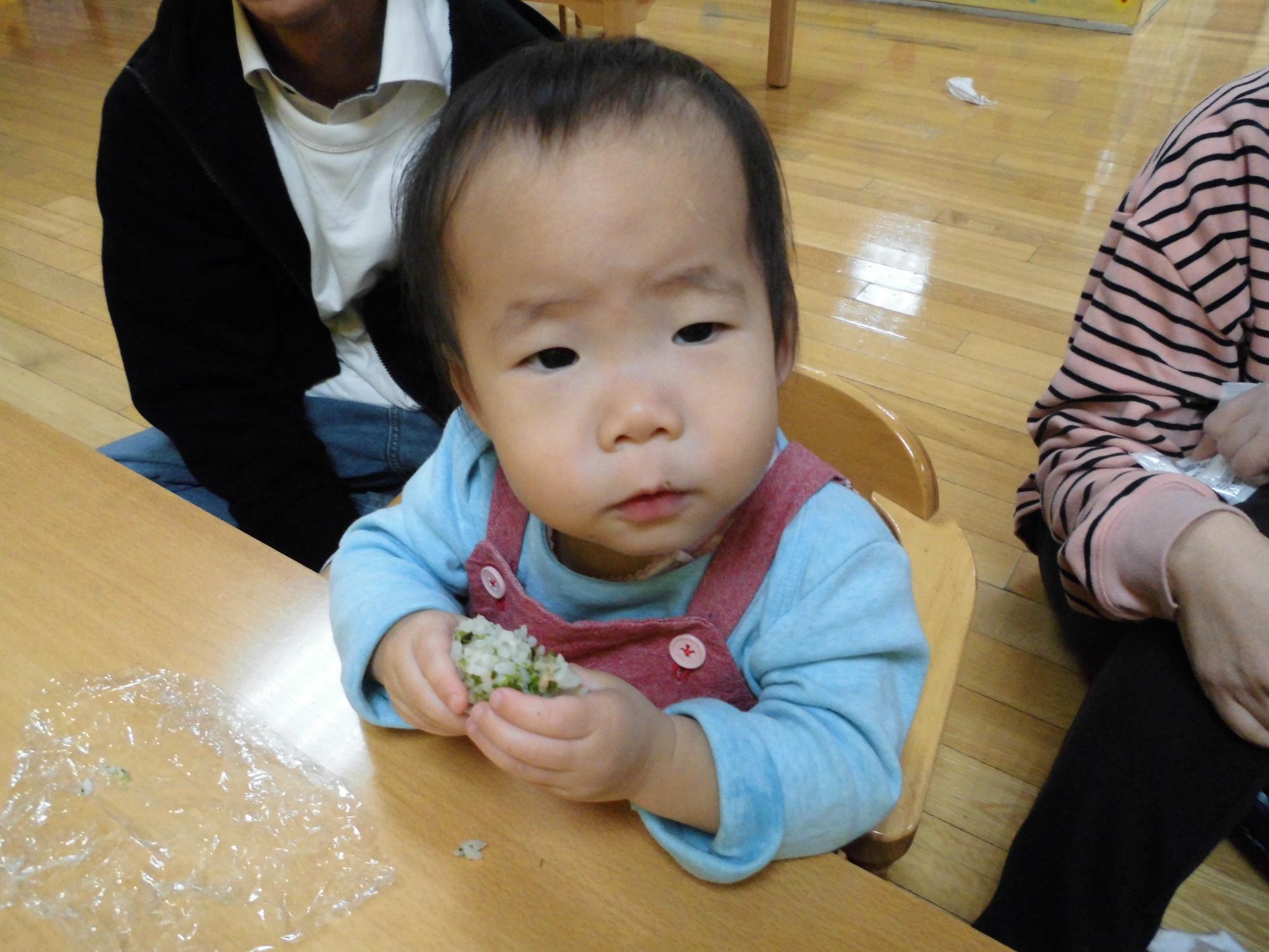 おにぎりを両手で持って食べる子供