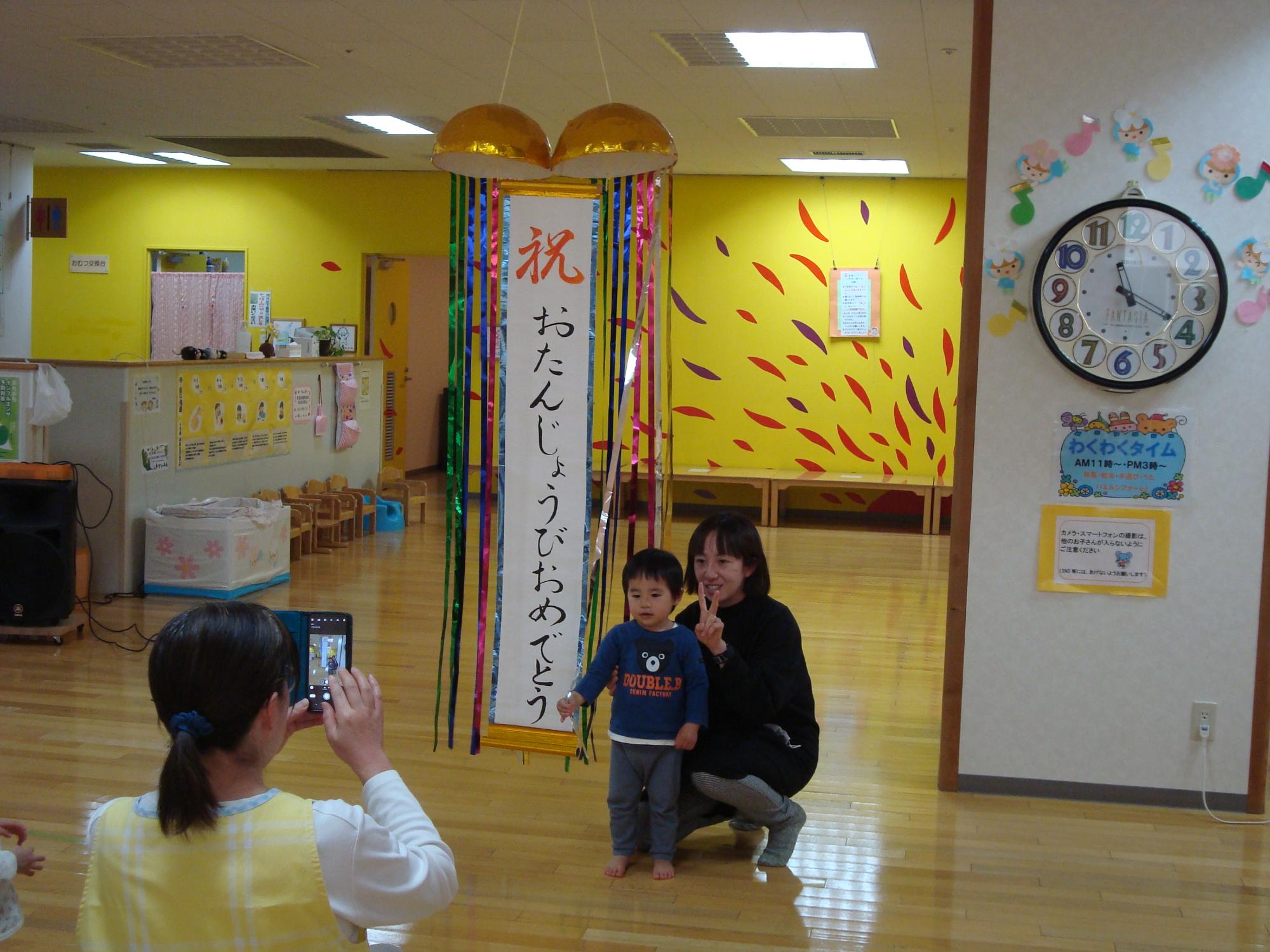 くす玉の前でしゃしんを撮る親子