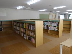 茶色い本棚に沢山の本が並んだ図書室の写真