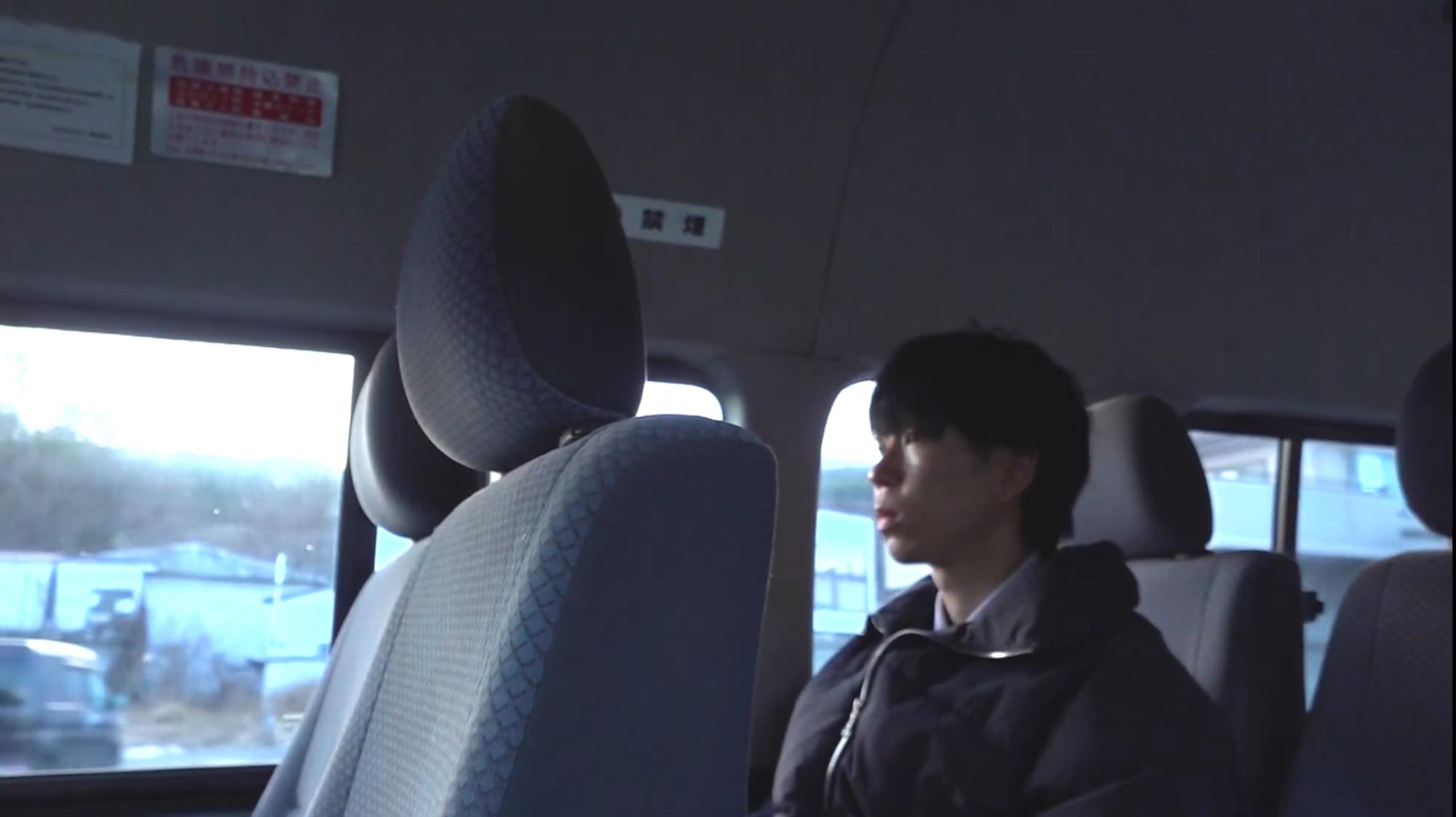 車内の座席に着席する男性の写真