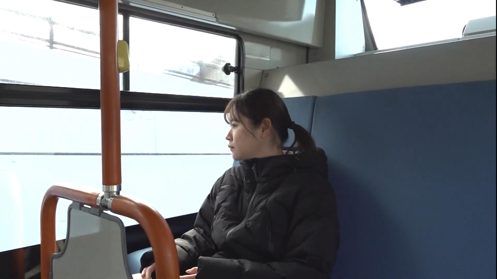 バス車内の座席に着席する女性の写真