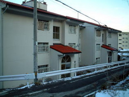 赤い屋根と白い壁の3階建ての団地の写真