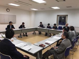 室内で机を四角く並べて会議をしている写真