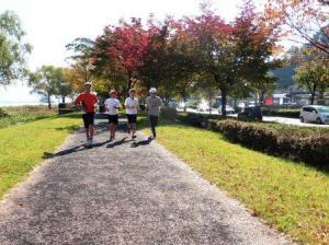 マラソン大会で4人のランナーが諏訪湖畔のコースを走っている写真