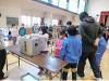 体育館で子供たちが投票箱に札を入れている写真
