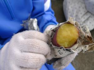 手袋をした人が新聞紙で巻かれた焼き芋を持っている写真