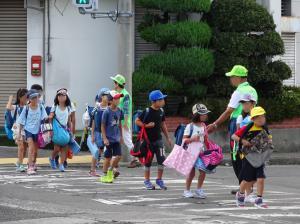 横断歩道を大人に見守られながら渡る子どもたちの写真