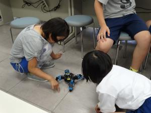 子どもたちが床でロボットを動かしている写真