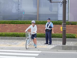 ヘルメットをかぶった子どもが自転車を引いて横断歩道を渡ろうとしている写真