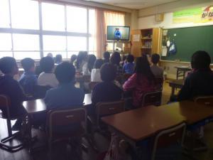 演説する生徒が映るテレビ画面を見つめる生徒たちの写真