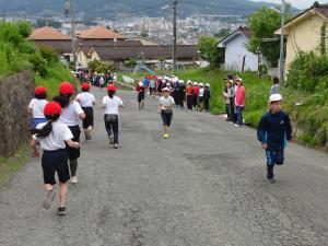走る子ども達を別の学年の子ども達が応援している写真