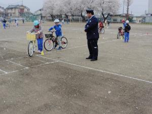 校庭内で自転車の指導を受ける生徒たちと警察官の写真