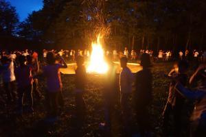 キャンプファイヤーで火を囲っている生徒たちの写真