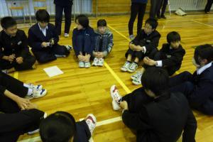 体育館で生徒たちが輪になって座って話し合っている写真