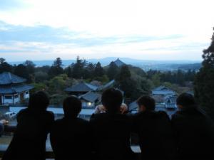 修学旅行で生徒達が高台から寺社を眺めている写真