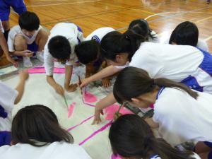 西中祭の準備で多数の生徒が布に文字を描いている写真
