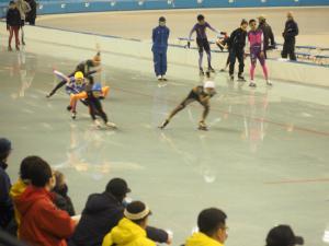 リンク上で選手たちが競い合って滑走している写真