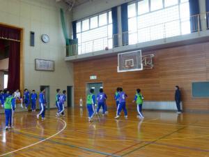 体育館で生徒たちがバスケットボールの試合をしている写真