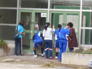 生徒が親子で校舎入口のガラスを拭いている写真