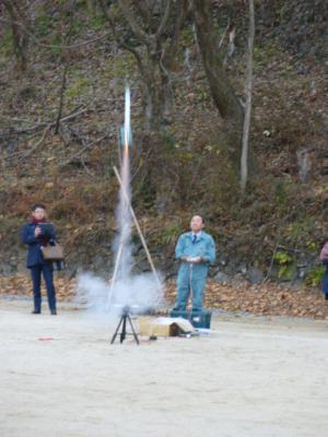 グラウンドに設置されたでロケットが発射している写真
