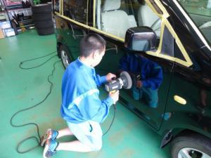 自動車工場内で男子生徒がポリッシャーをかけている写真
