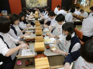大勢の生徒がそれぞれ並んで食事をしている写真