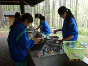 森の中の炊飯場で数人の生徒が料理をしている写真