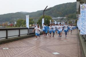 生徒たちが諏訪湖に面した道路を走っている写真