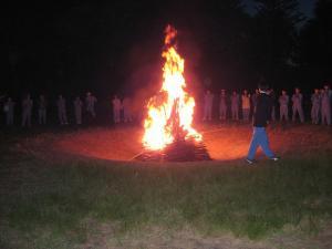 キャンプファイヤーの火の周りに生徒たちが輪になっている写真