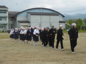 頭にタオルを巻いた生徒たちが列になって校庭を歩いている写真
