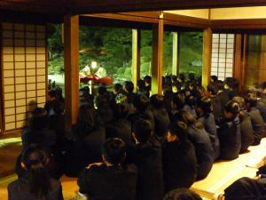 お寺で生徒たちが座って庭を眺めている写真