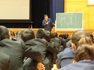 体育館のステージ前で岡谷警察署の方が生徒たちに話をしている写真