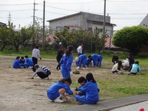 校庭で生徒と親たちが草むしりをしている写真