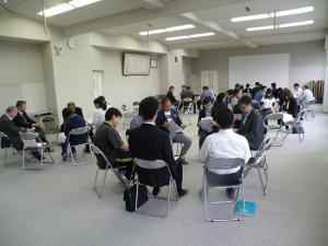 広い会議室でいくつかのグループに分かれて大人たちが意見を交換しあっている写真